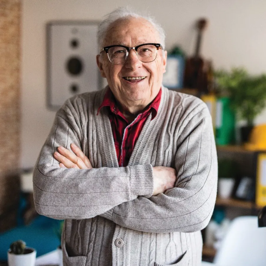 An elderly man crossing his arms and smiling.